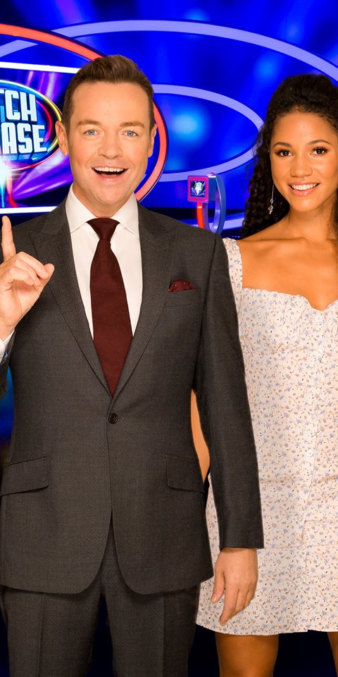 Presenter posing with three contestants smiling at the camera.